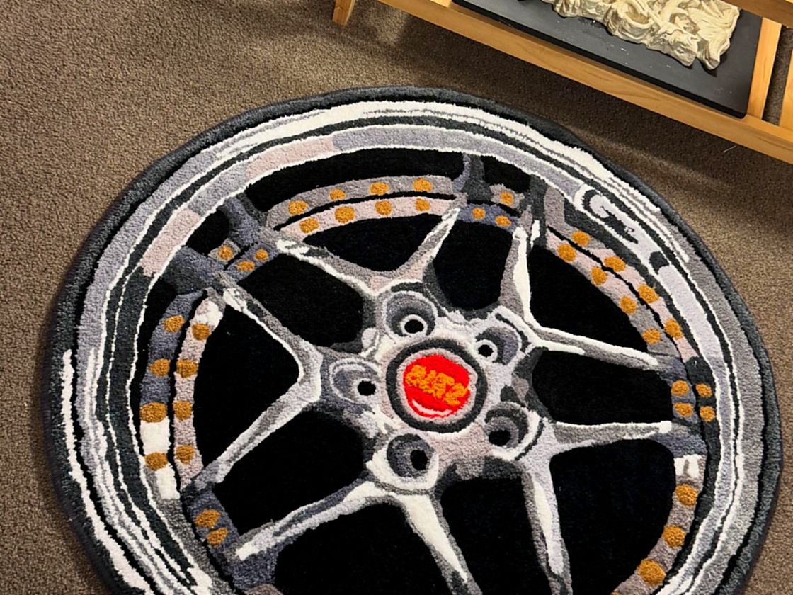 A round custom rug tufted as a detailed car wheel, cut to its own outline