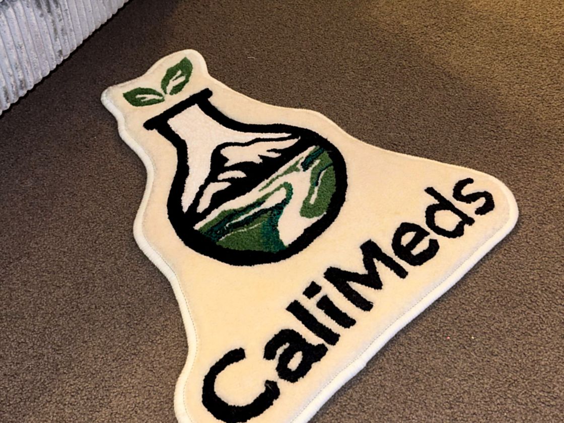 A hand-tufted Cali Meds logo rug, cut to the shape of the brand mark
